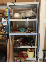 Front view of plastic shelving unit filled with various items across three shelves including bags, tools, and containers.