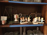 Shelf with three brass menorahs, ceramic figurines of children, Jefferson Cup with certificate, a scale and decorative plates