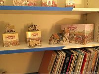 Four David Winter cottages displayed on shelving with their original boxes, showing decorative collectible houses.