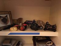 Wide view showing shelf with animal figurines including a framed stained glass cat, painted wooden animals, and ceramic and glass figurines.