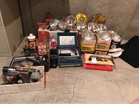 Wide view of automotive parts and tools including headlights, manuals, tune-up equipment, and other supplies arranged on ground.