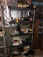 Four shelves stacked with office supplies including binders, notebooks, organizers, and miscellaneous electronics.