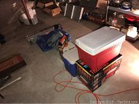 Area with stacked items including coolers and boxes in a dimly lit room, no table or chairs visible here.