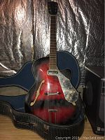 Full front view of sunburst guitar inside open hard case