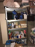 Full view of shelving unit containing various painting supplies such as paint cans, brushes, rollers, tape, compound, and storage containers as well as lunch boxes and coolers