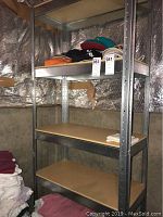 Metal shelving unit 36x16x72 with three shelves containing some personal items for photo context