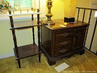 Both the end table with drawers and cabinet, and the wood stone top stand adjacent to it near the stair railing.