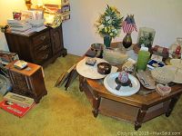 Room corner with the octagonal coffee table holding various decorative items and a wooden end table with drawers and cabinet next to it.