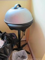 Side view of the George Foreman grill on a metal stand with cross base.