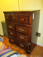 Front and side view of dark wooden dresser showing four drawers with brass colored hardware and overall condition including chips and scratches.