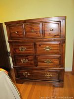 Front view of wood dresser showing four drawers with brass-colored knobs and handles, damage visible on surface.