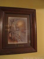 Framed print of bird on branch in winter landscape with wooden frame