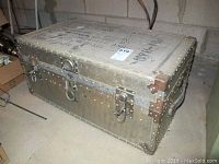 Front view of the metal trunk showing riveted exterior and latches