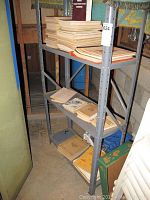 Wide shot of metal shelving unit holding stacks of military manuals and books in a basement or storage area.