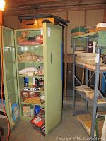 Photo showing the olive green metal cabinet with both doors open, containing various miscellaneous items.