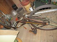 Side view of the Huffy bicycle showing frame, pedals, and chain area with rust and soiling.