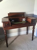 Open view of antique secretary desk showing turned legs, drop front opened exposing inner compartments and small drawers.