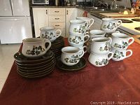 18 ceramic cups and 16 matching saucers with Denby Shamrock pattern arranged on table.