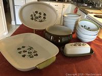 Photo showing the entire Denby Shamrock pottery set including two bakers, 12 fruit bowls, a vegetable dish, and butter dish, arranged on a kitchen counter.