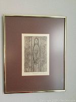 Framed monoprint with stylized female figure titled 'Angelina' inside a gold-tone frame with reddish mat.
