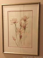 Photo of framed watercolor painting showing delicate magnolia flowers in pink tones with a double mat and metallic frame.