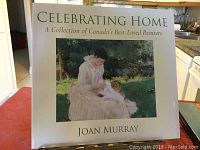 Photo of large hardcover art book titled 'Celebrating Home: A Collection of Canada's Best-Loved Painters' by Joan Murray with a painting reproduction on the front cover.