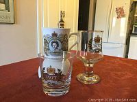 Three commemorative drinkware items for Queen Elizabeth II's Silver Jubilee 1977, placed on a table against a home background.
