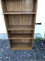 Front view of the wooden bookshelf showing five shelves total with two adjustable shelves visible through side peg holes