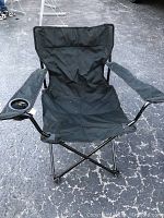 Front view of the black folding camp chair showing the seat, armrests, and cup holder on the left armrest.