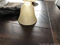 Light cover made of frosted glass, seen from above on dark table surface.