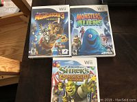 Photo showing three Nintendo Wii game cases: Madagascar 3, Monsters vs Aliens, and Shrek's Carnival Craze.