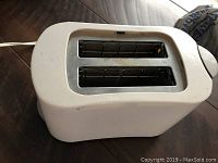 Side view of white two-slot toaster showing power cord and lever.