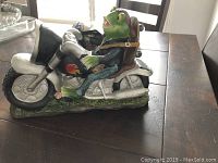 Side view of the frog on the motorcycle solar garden ornament showing details of the figurine and motorcycle.