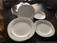 Photo showing Mikasa Caviar place setting including saucer, dinner plate, salad plate, and soup bowl with silver trim on white background.