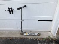 Full side view of a silver Skator scooter with worn handgrips and two wheels on ground.