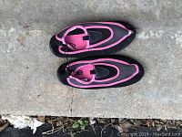 Top view of pair of pink and black water shoes placed on concrete surface, showing overall condition and color.