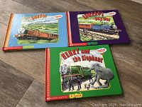 Three hardcover children's books with Thomas the Train stories: Leaves / Off the Rails, Edward's Day Out / Edward and Gordon, Henry and the Elephant / Fire Engine, showing colorful illustrated covers.