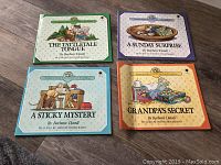 Four softcover children's books from the Christopher Churchmouse Classics series arranged in a grid on wooden floor, showing the front covers of 'The Tattletale Tongue,' 'A Sunday Surprise,' 'A Sticky Mystery,' and 'Grandpa's Secret.'