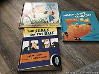 Photo showing three hardcover children's books: 'Kiss the Cow!', 'The Seals on the Bus', and 'Where's My Quack?'. Covers are colorful and illustrated with animals and children.