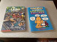 Photo of two softcover children's books on a surface: The Littles Give a Party and Garfield Big Book of Super School Excuses.