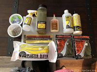 Photo showing the entirety of the Woodland Scenics model railroad supplies, including the plastic container of foam nails, a sprayer bottle, jars and packets of various turf types, glues, plaster cloth, and foam pencils.