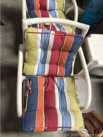 Top view of one rattan swivel chair showing the colorful striped cushions on seat and backrest.
