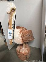 Front angle view showing the pelican statue with visible paint chipping, standing on a round base.