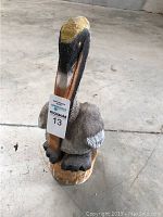 Front view of painted wooden pelican statue with MaxSold tag.