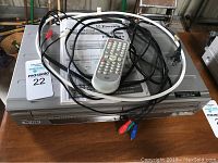 Front view of Emerson VCR and DVD player combo with remote, power and component cables on top, and user manual.