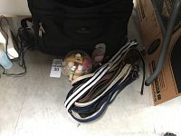 Photo showing black travel bag behind several belts in different colors, and a jar containing travel shampoo and other small toiletry bottles