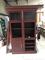 Front view of two matching wooden bookcase cabinets with adjustable lighted top, glass doors on upper section, one cabinet lower door, the other open shelving.