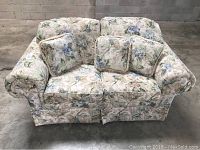 Front view of floral print loveseat sofa with two seat cushions and four matching throw pillows.