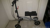Full side view of Nova knee scooter showing metallic silver frame, black knee rest, and front and rear wheels.