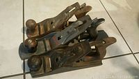 Three vintage metal and wood hand planes arranged in a row showing condition and design.